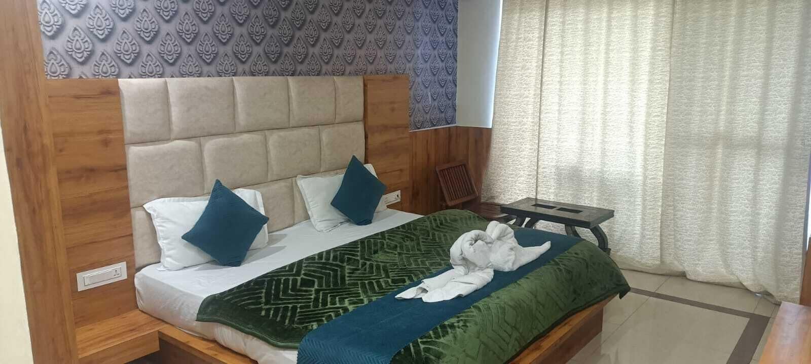 A bed with a headboard, pillows, a blanket, and a wooden nightstand.