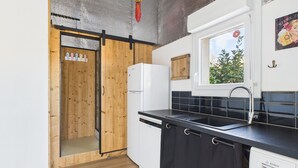 Een moderne keuken met houten kastjes, een zwart aanrecht en een Bosch vaatwasser.
