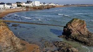 A coastal view with rocky shores, clear water, and buildings in the background. - Chalet for 6 in St-Hilaire - Heated swimming pool (Saint-Hilaire-de-Riez)