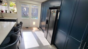 Eine moderne Küche mit dunkelblauen Schränken, einem Edelstahl-Kühlschrank und einem Oberlicht über dem Essbereich.