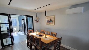 Ein Essbereich mit Holztisch und -stühlen, einem Deckenventilator und einer Wand-Klimaanlage.