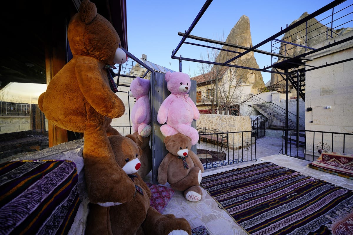 Une pièce dotée d’une grande fenêtre, d’un lit recouvert d’une couvre-lit à motifs, et offrant une vue sur une montagne et un bâtiment au loin.