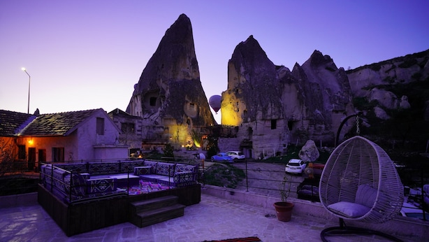 A rooftop terrace with a seating area, a hanging chair, and a view of rock formations. - Glory Art Stone House (Nevsehir)