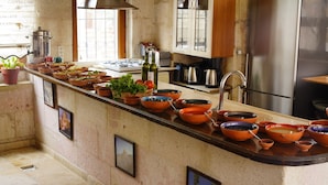 A kitchen with a long counter, various cooking utensils, and a refrigerator. - Glory Art Stone House (Nevsehir)
