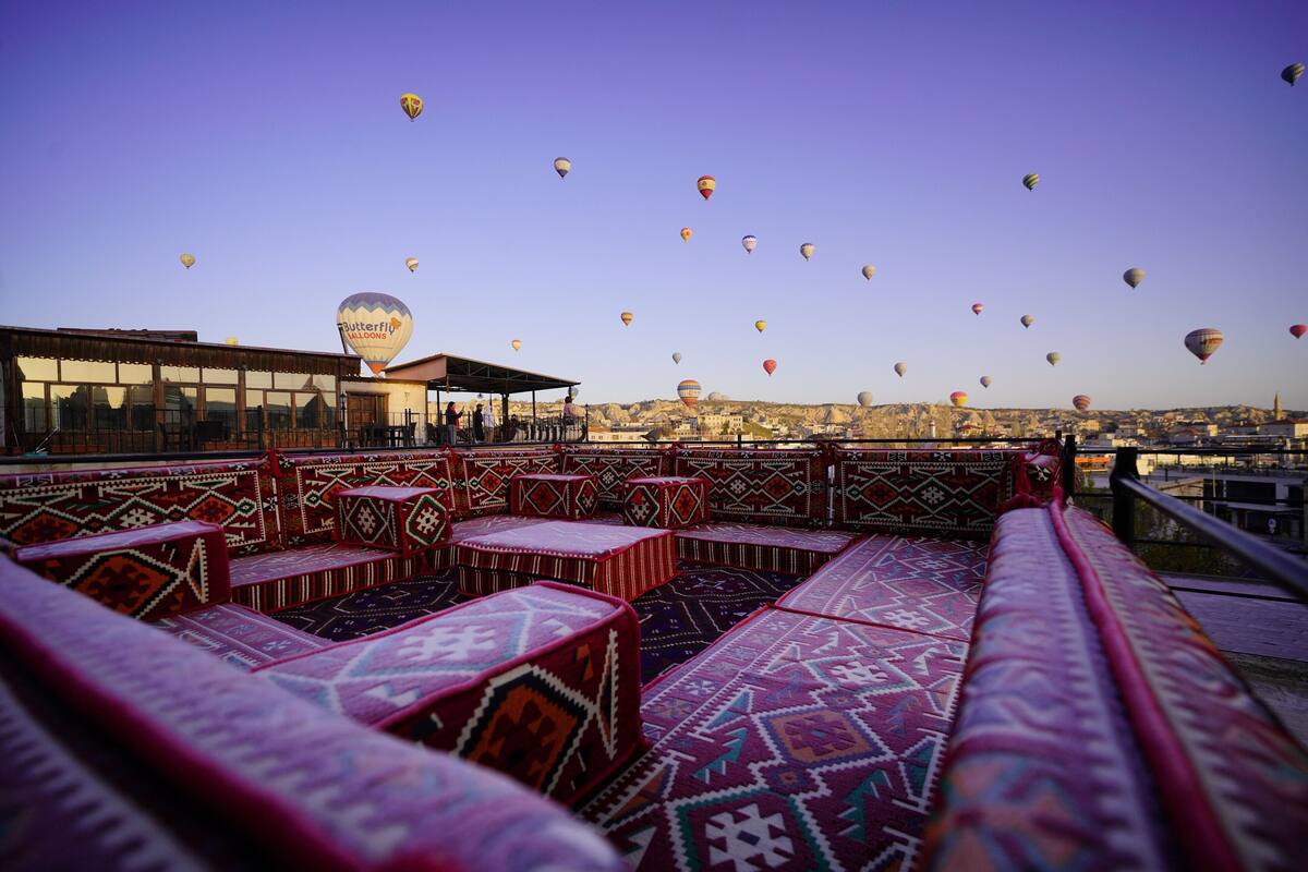 Une terrasse sur le toit, dotée de sièges aux motifs originaux et offrant une vue sur des montgolfières au loin.