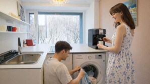 A modern kitchen with a coffee machine, a washing machine, and a window with a view of trees. - Maison de Pepperoni Cheongdam N.5 Romantic Retreat in Gangnam, Garden View! (서울시)