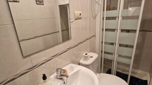 A bathroom with a sink, toilet, and shower area.