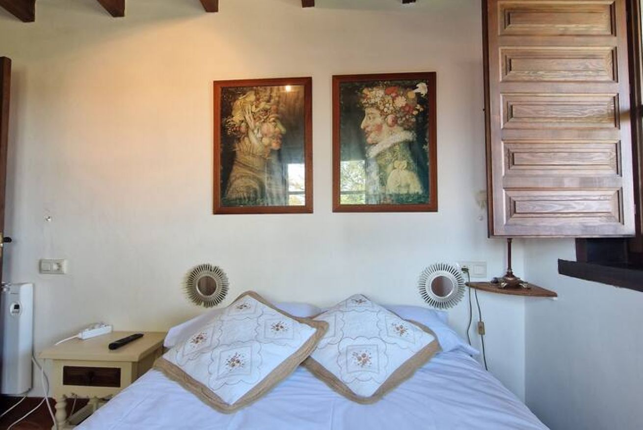 Une chambre à coucher avec un lit, deux tableaux accrochés au mur, des lampes de chevet et un mur recouvert de panneaux en bois.