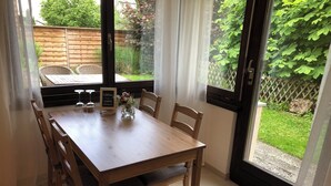 A wooden dining table with chairs, a chalkboard sign, and a vase of flowers. - Beautiful apartment with garden seating area in Rapperswil-Jona (Rapperswil-Jona)