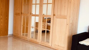 A spacious room with a large wooden wardrobe, a black sofa, and a tiled floor. - Beautiful apartment with garden seating area in Rapperswil-Jona (Rapperswil-Jona)