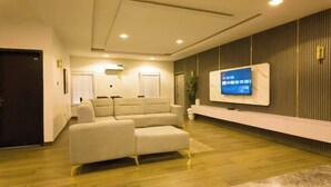 Una sala de estar moderna con un televisor de pantalla plana grande montado en la pared, un sofá seccional color beige y piso de madera.