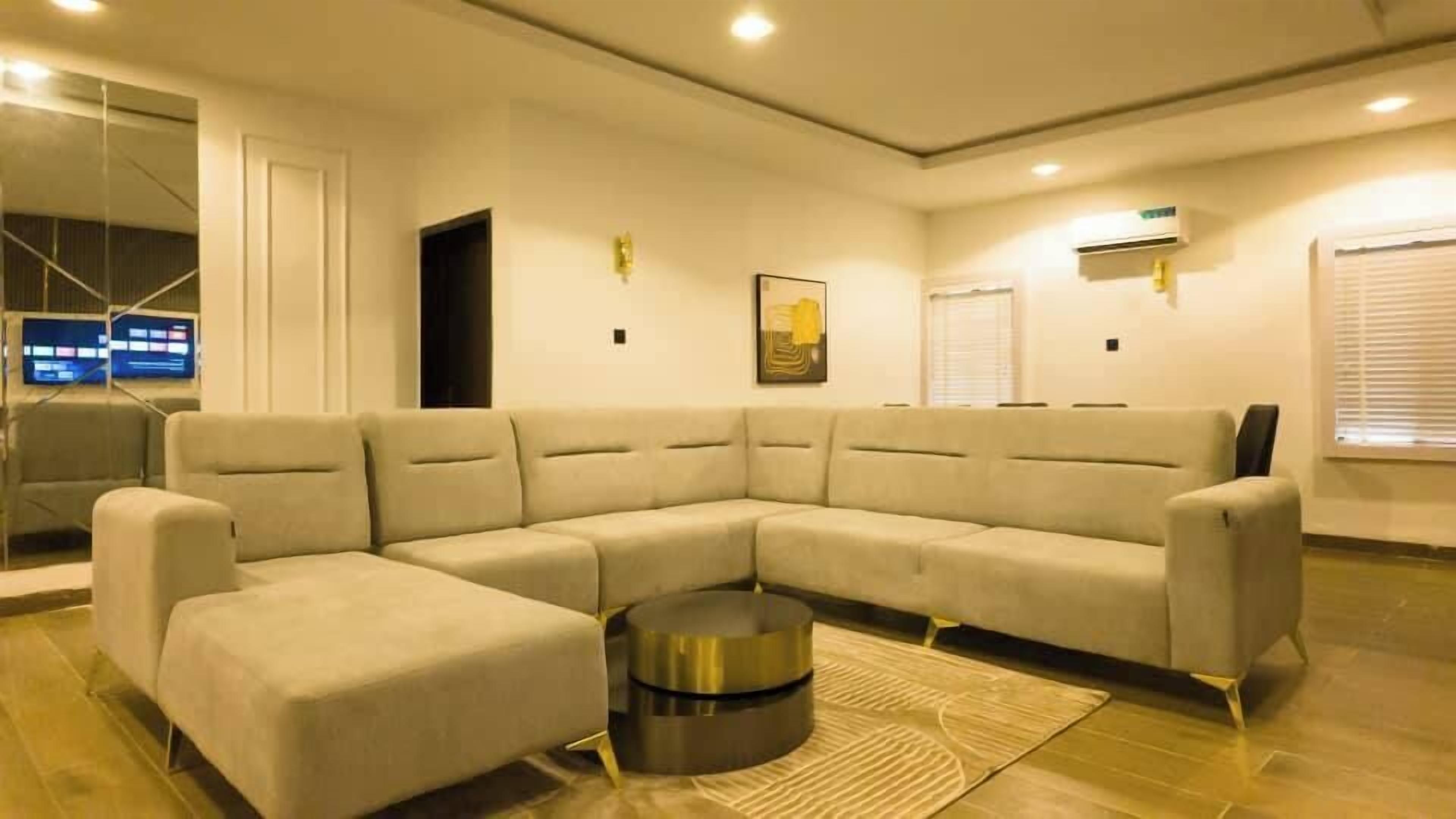 A modern living room with a beige sectional sofa, a round coffee table, and a glass partition.