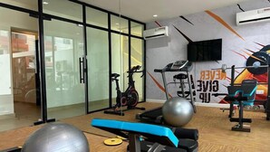 Un gimnasio con equipo de ejercicio, un espejo grande y un cartel motivacional.