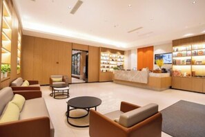 Et hotellobby med reception, siddeområde og udstilling af faciliteter.