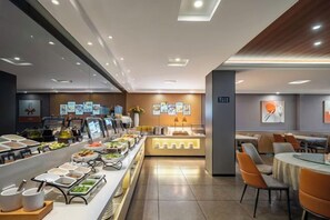 En buffet med forskellige madstationer og et siddeområde med borde og stole.