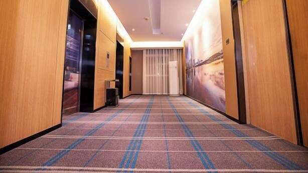 A hotel hallway with wooden walls, a patterned carpet, and a large window with a view of a cityscape. - Century Star Boutique Hotel (Henan People's Hospital Zijingshan) (Zhengzhou)