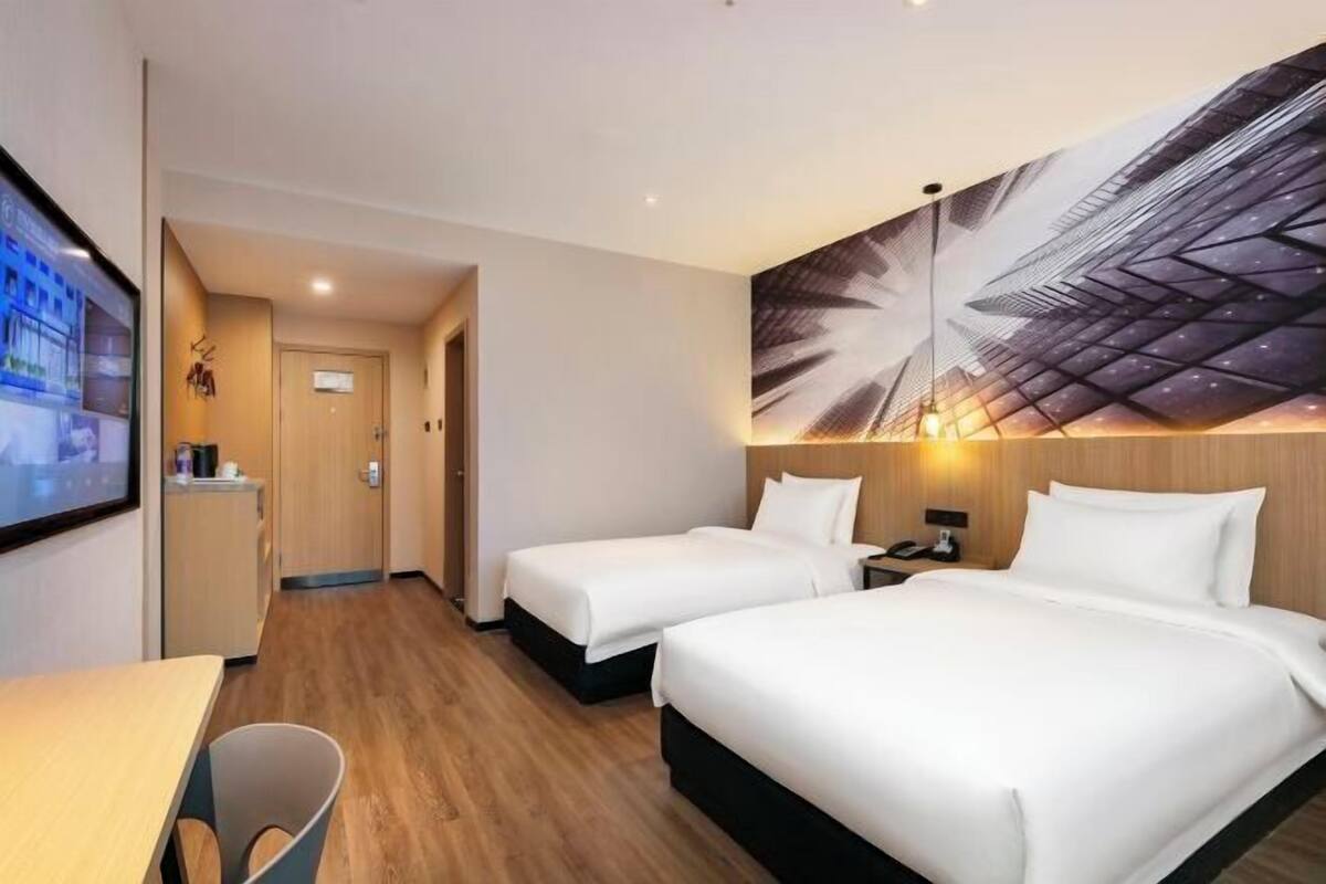 Una habitación de hotel con dos camas, un escritorio y una televisión.