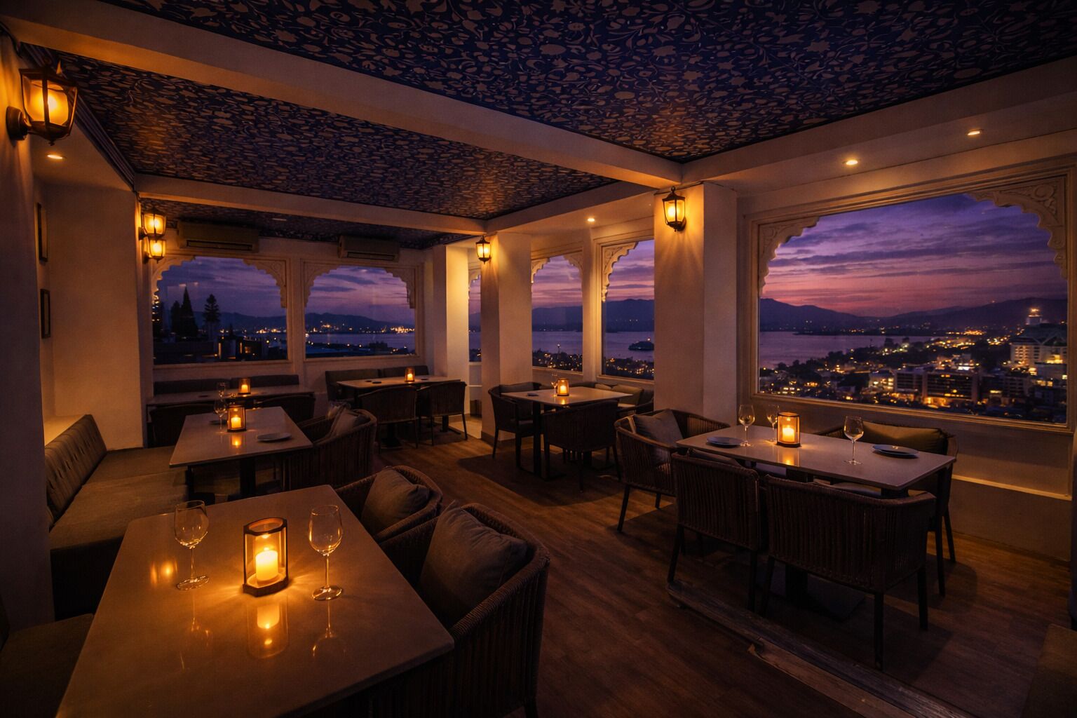 A restaurant with tables and chairs, candles, and a view of a cityscape at dusk.