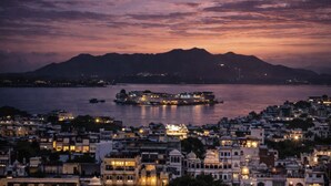 Una vista urbana al capvespre amb un riu, barques i edificis.