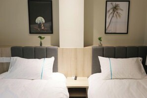 A hotel room with two beds, a nightstand, and framed artwork on the walls.