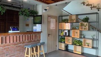 A reception area with a brick counter, two bar stools, a computer, and a wall-mounted TV.