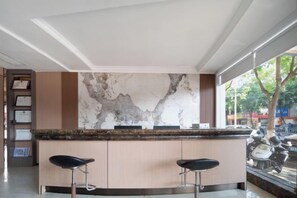 A bar area with a marble backsplash, two bar stools, and a view of the street outside. - Milan Theme Hotel (Xianju)