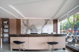 A bar area with a marble backsplash, two bar stools, and a view of the street outside.