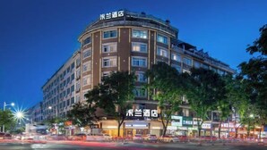 Un hotel de varios pisos con fachada curva, múltiples balcones y señalización iluminada.