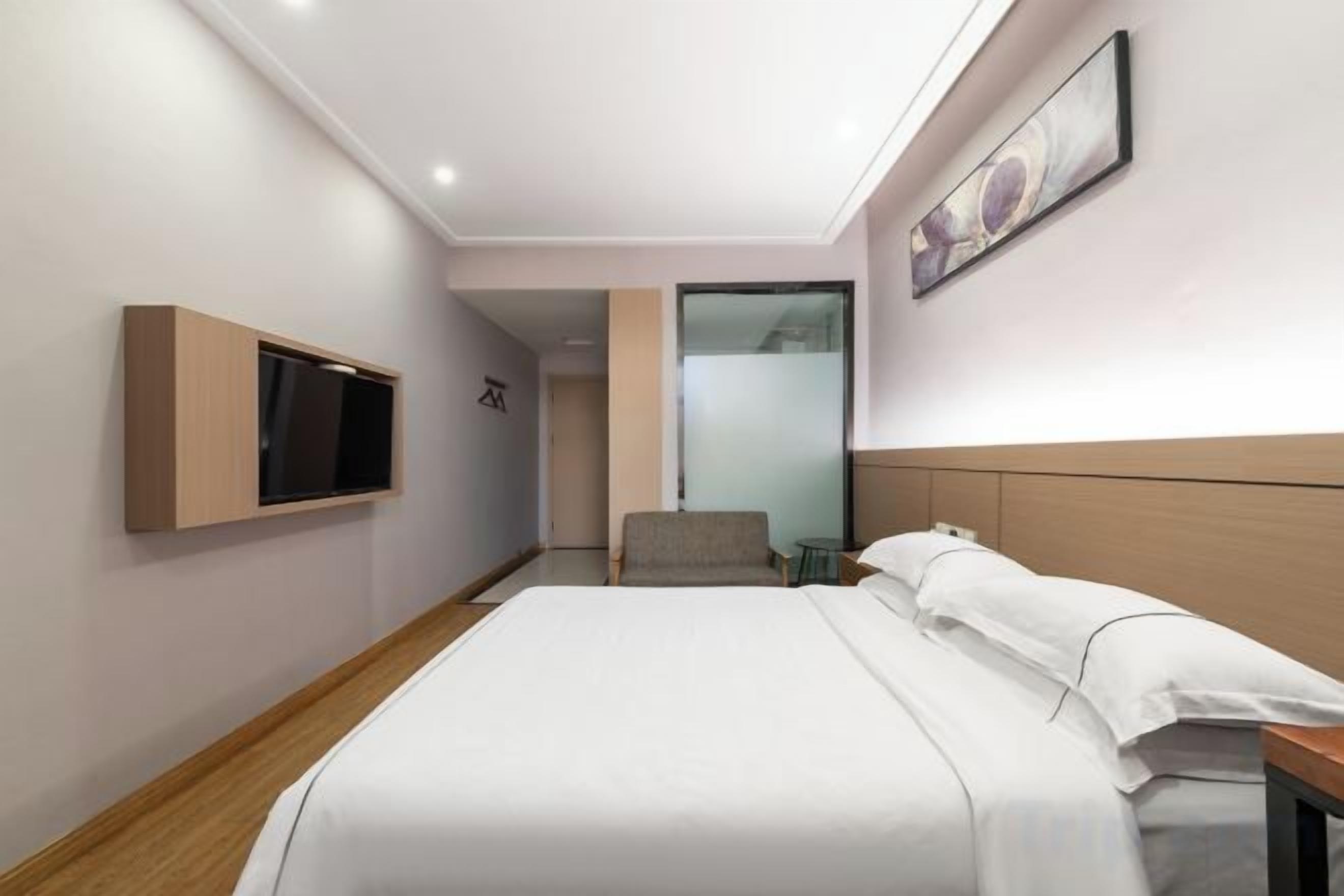 Une chambre d’hôtel avec un lit, un téléviseur fixé au mur et une petite table.