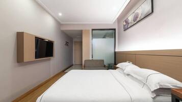 Une chambre d’hôtel avec un lit, un téléviseur fixé au mur et une petite table.