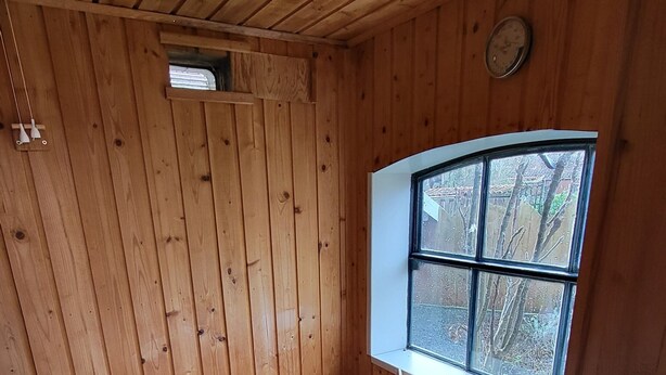 A wooden sauna with benches, a window, and a wooden bucket. - Vacation apartment Dörpschipper in the smallest warf village of the Krummhörn (Krummhörn)