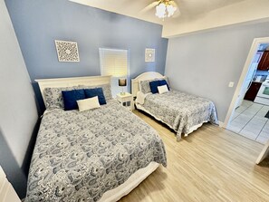 A bedroom with two beds, a nightstand, and a ceiling fan.