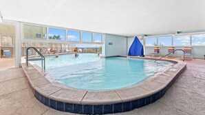 Una piscina interior con agua cristalina, rodeada de sillas de descanso y un solárium con baldosas.