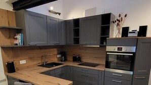 Eine moderne Küche mit grauen Schränken, einer Holzausziehtafel und einem eingebauten Backofen.