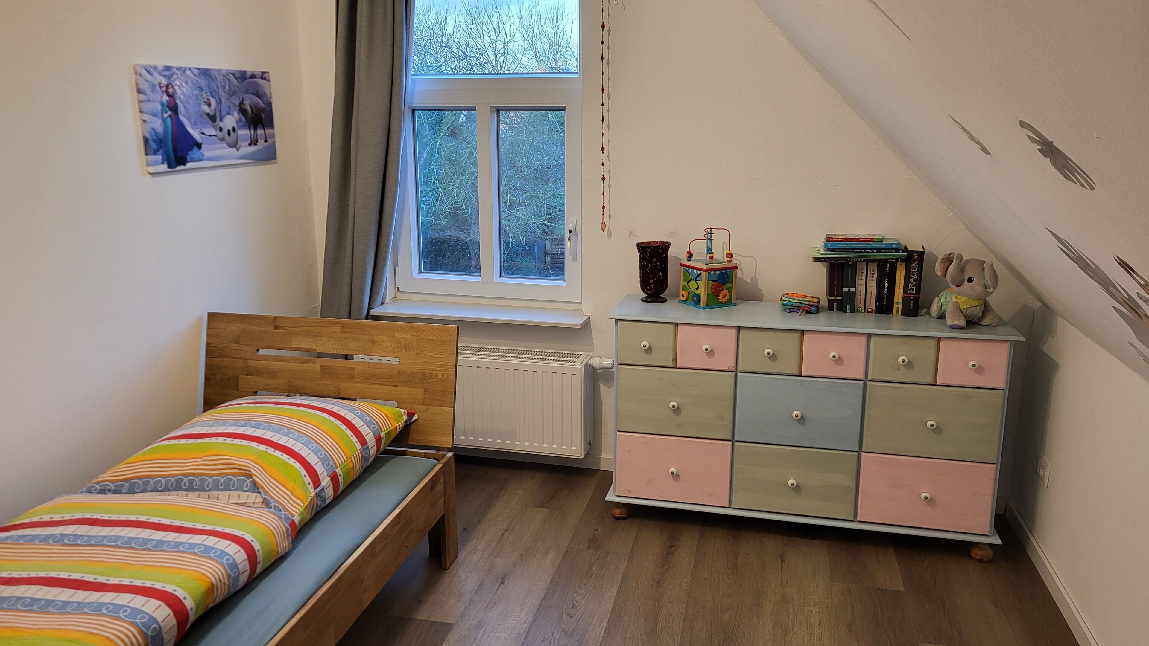 A bedroom with a bed, a dresser, and a radiator.