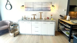 A modern kitchen with a central island, white cabinetry, and a coastal-themed wall art above. - Apartment Near Boat Club in Middelkerke (Middelkerke)