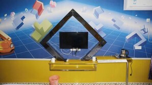 A reception area with a blue tiled wall, a black framed television, and a yellow counter. - Chenxiang Fashion Hostel (Shanghai)