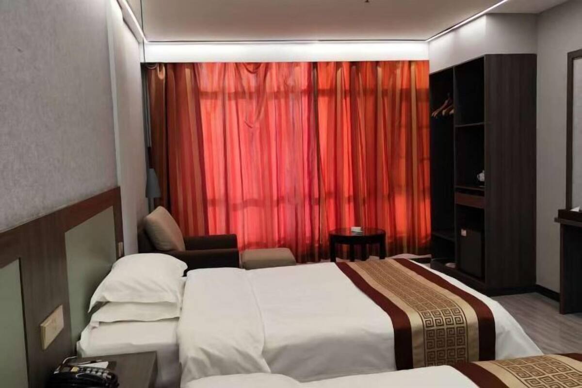 A hotel room with a bed, a wardrobe, a small table, and a chair.