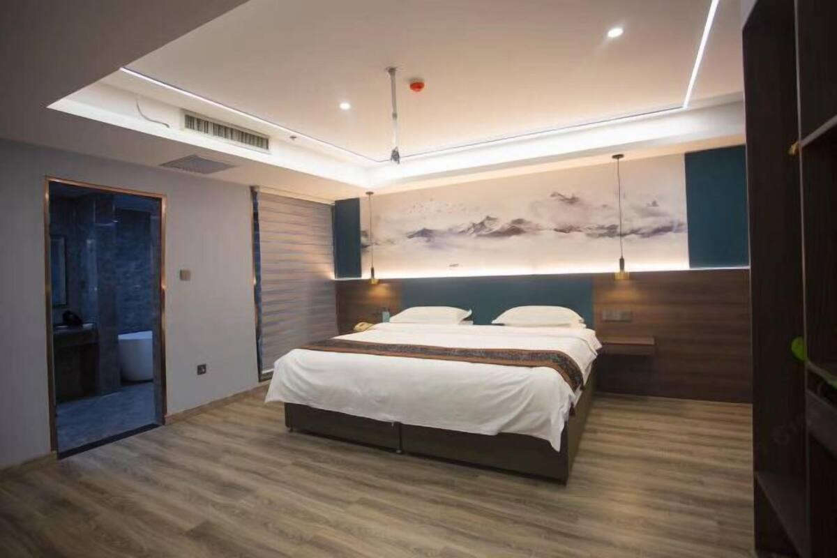 A modern bedroom with a large bed, a wall-mounted artwork, and a ceiling light fixture.