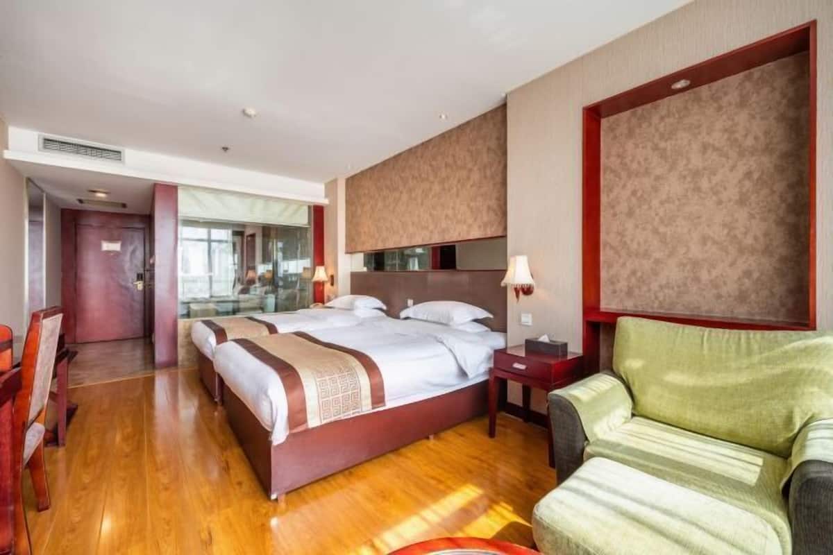 Habitación de hotel con una cama grande, un escritorio, una silla y un espejo.