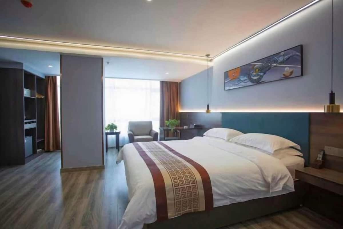 Una habitación de hotel moderna con una cama grande, un escritorio y vistas al pasillo.