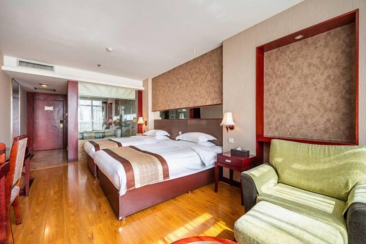 A hotel room with a large bed, a desk, a chair, and a mirror.