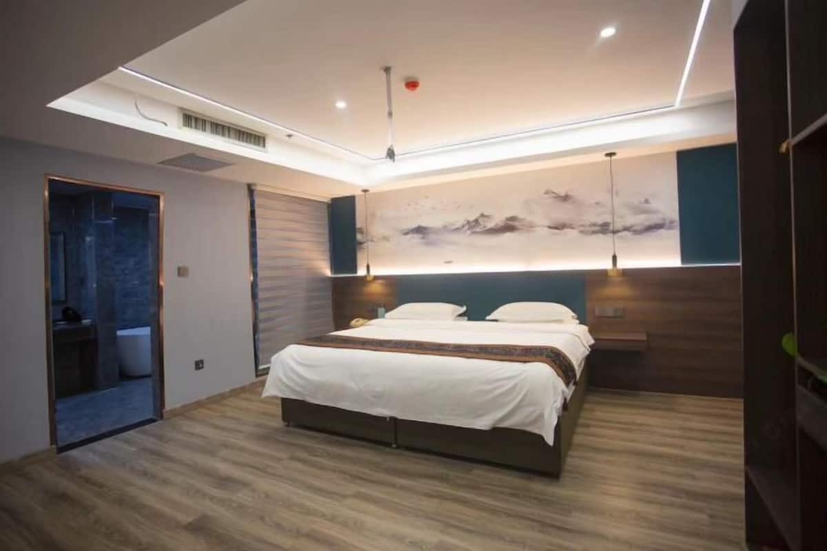 Un dormitorio moderno con una cama grande, una obra de arte en la pared y una lámpara de techo.
