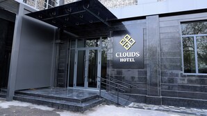Der Eingang zum Clouds Hotel mit modernem Design, mit einer Glastür und einer Metalltreppe, die zum Eingang führt.