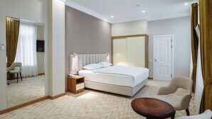 Ein Hotelzimmer mit einem großen Bett, Nachttisch, Stuhl und kleinem Tisch.