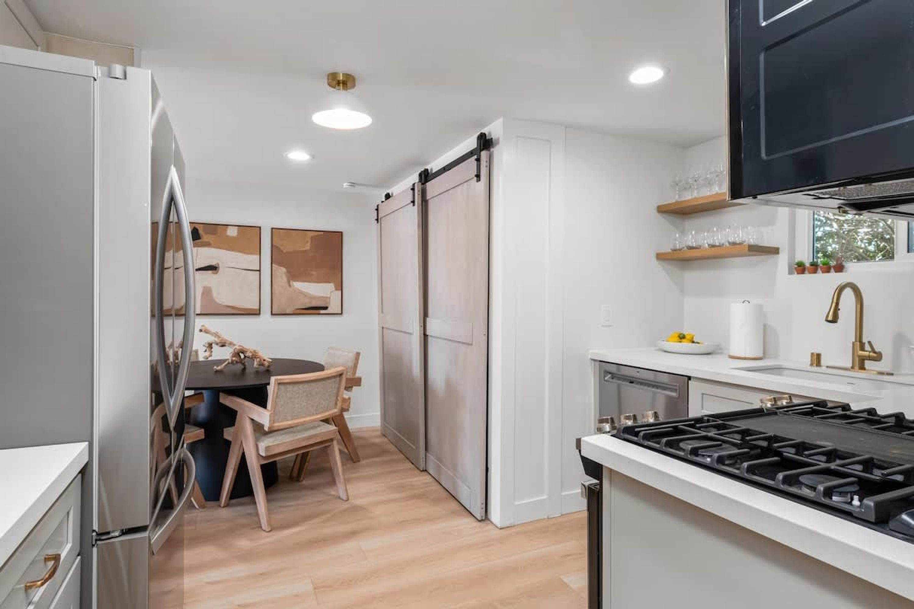 A modern kitchen with a central island, white cabinetry, and a gas stove.