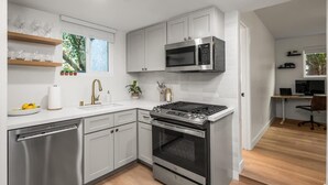 Una cocina moderna con armarios blancos, electrodomésticos de acero inoxidable y piso de madera.