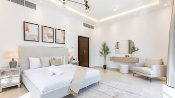 Quarto moderno com cama grande, mesas de cabeceira, escrivaninha, cadeira, espelho e planta em vaso.