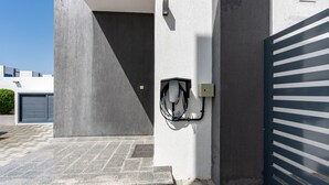 Entrada de un edificio moderno con fachada de hormigón, una puerta metálica y un enchufe en la pared.
