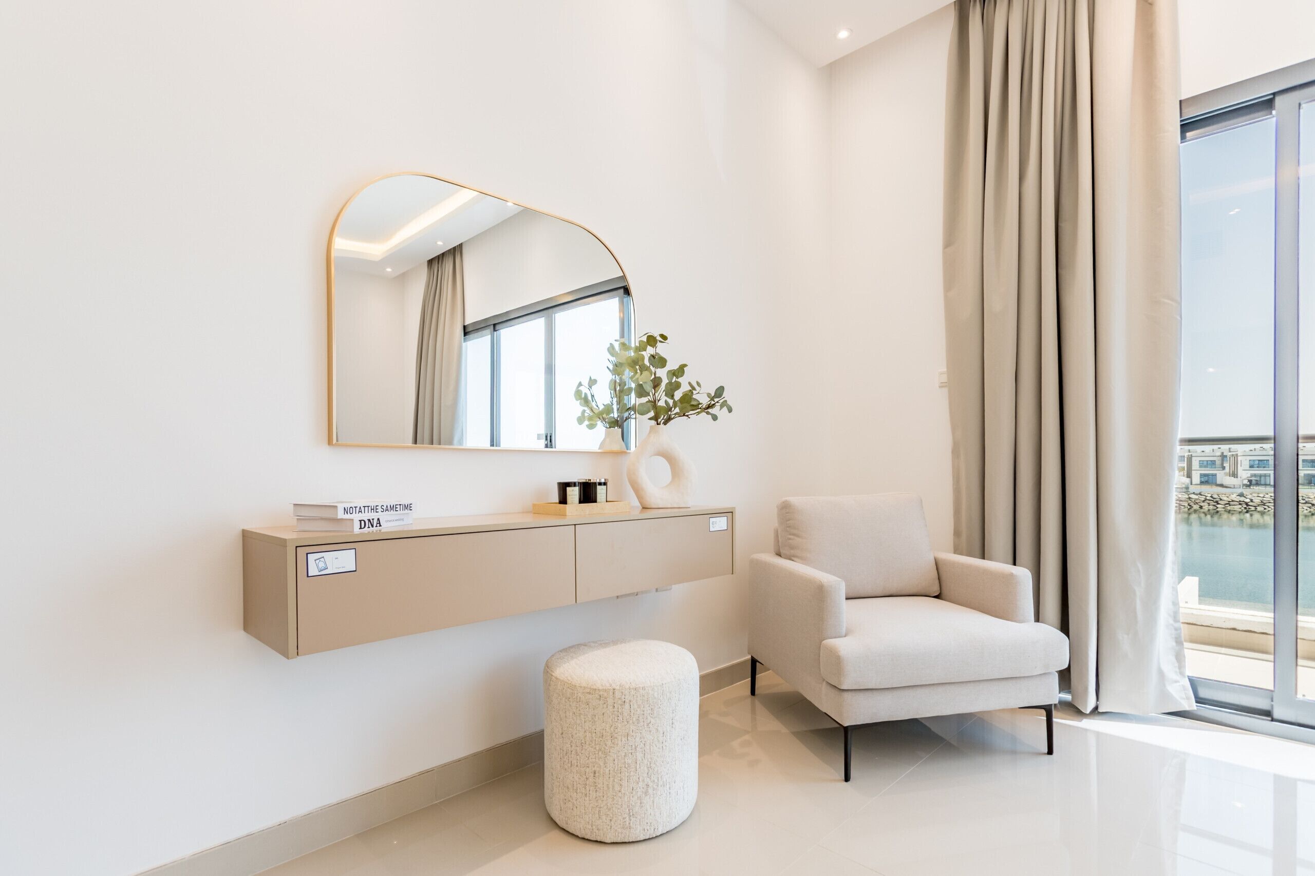 A modern bathroom with a vanity, a round stool, and a chair.
